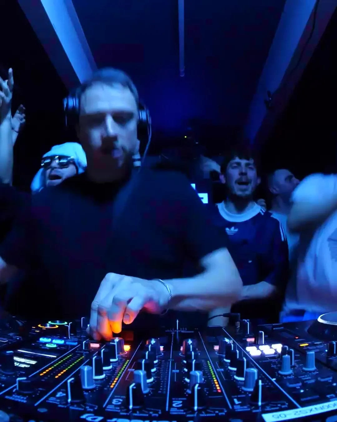 DnB Allstars 360° w/ Friction: DJ lit blue on the 360 decks, crowd around him