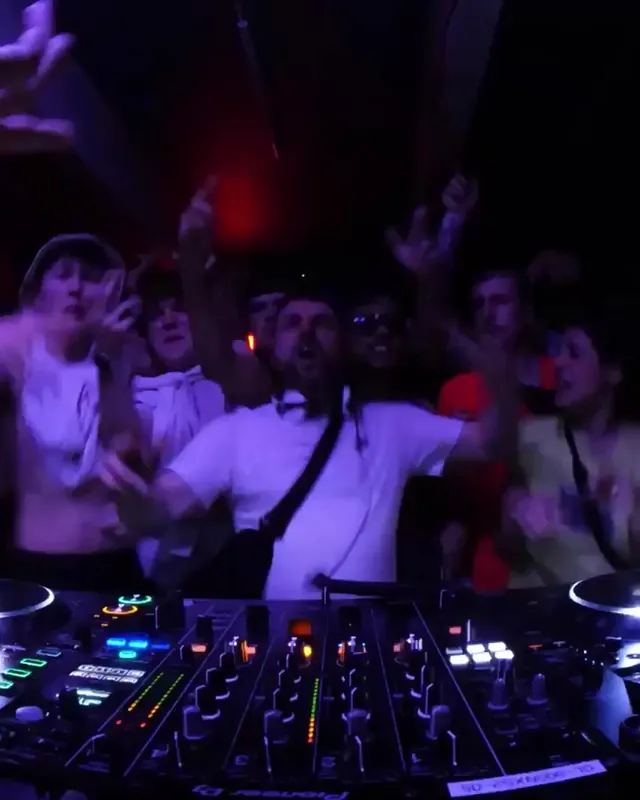 DnB Allstars 360° w/ Bou: DJ in white laughing on the 360 decks, crowd reaching in