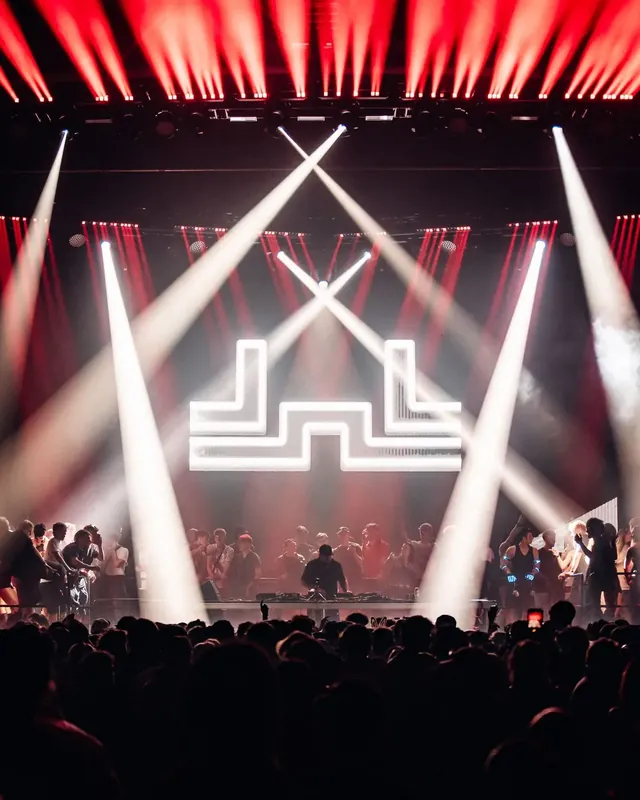 DnB Allstars: Auckland: Red and white beams framing neon dnb logo above crowd