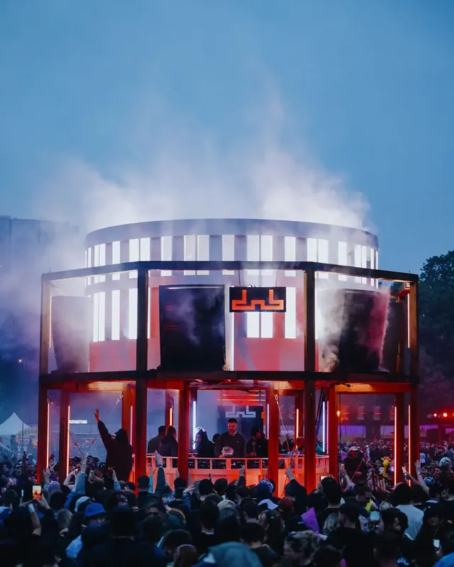 DnB Allstars Festival 2025: Round dnb main stage glowing through smoke at dusk over big crowd