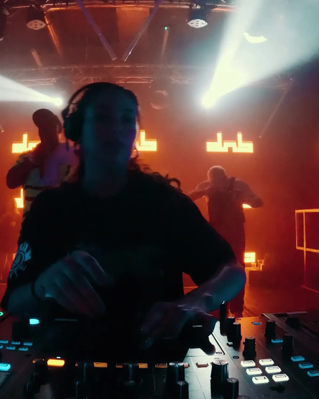 DnB Allstars NYE: London: DJ in orange light with the DnB Allstars logo behind