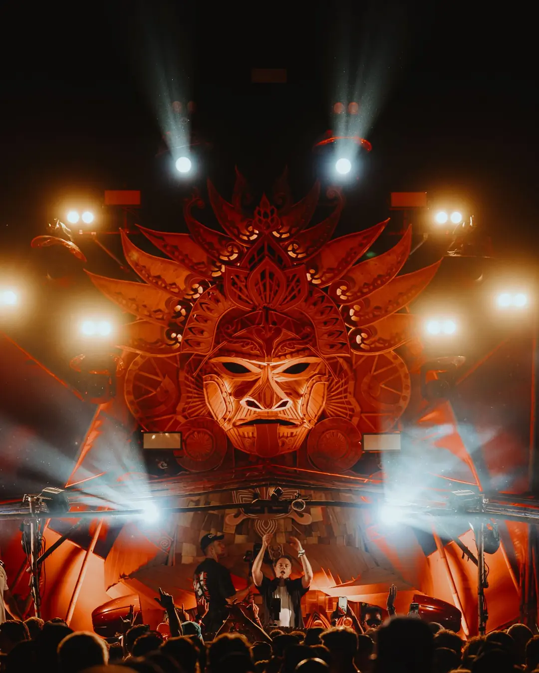 DnB Allstars: Thailand: Main stage mask blazing orange with beams, packed crowd below, instantly reads festival