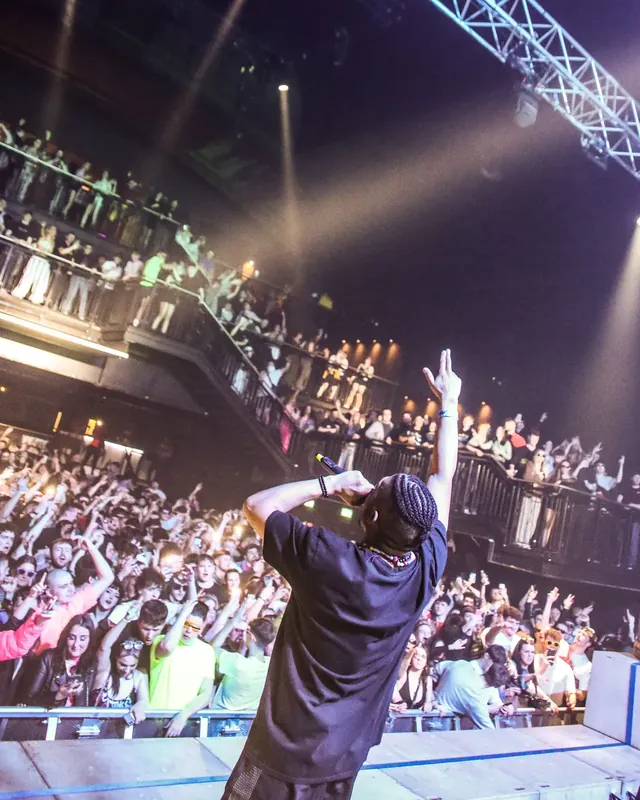 DnB Allstars x 30Hz: Newcastle: MC from behind, arm up to a packed crowd and balconies, big energy