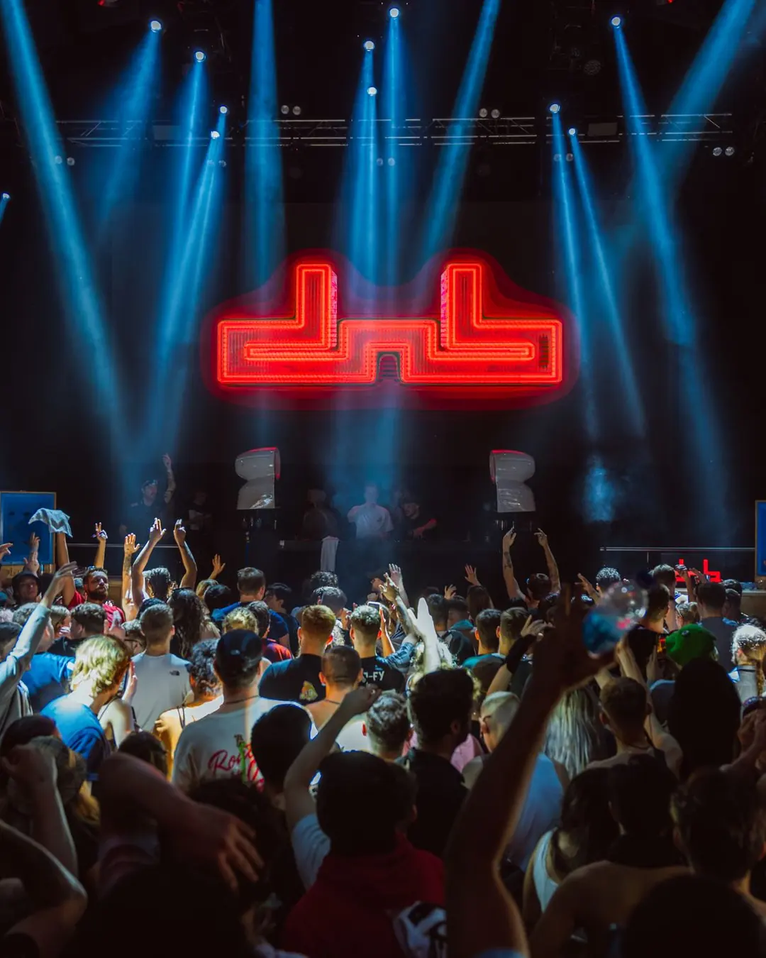 DnB Allstars x 30Hz NYD: London: Red neon dnb logo amid blue beams over packed crowd