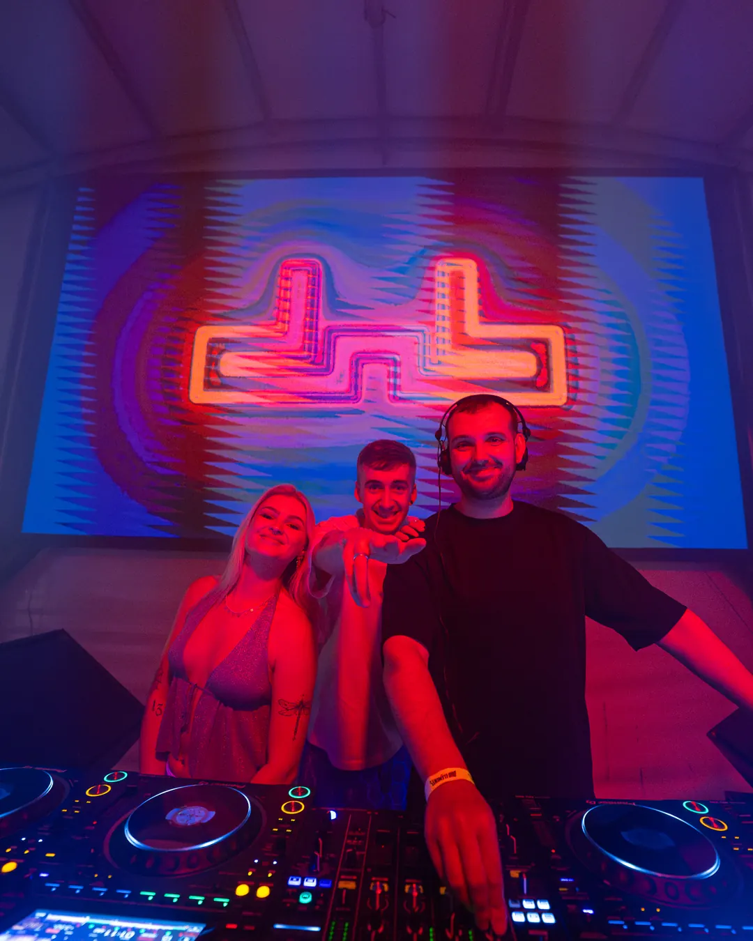 DnB Allstars x Dub Elements: Seville: DJ and friends in front of the neon DnB Allstars logo