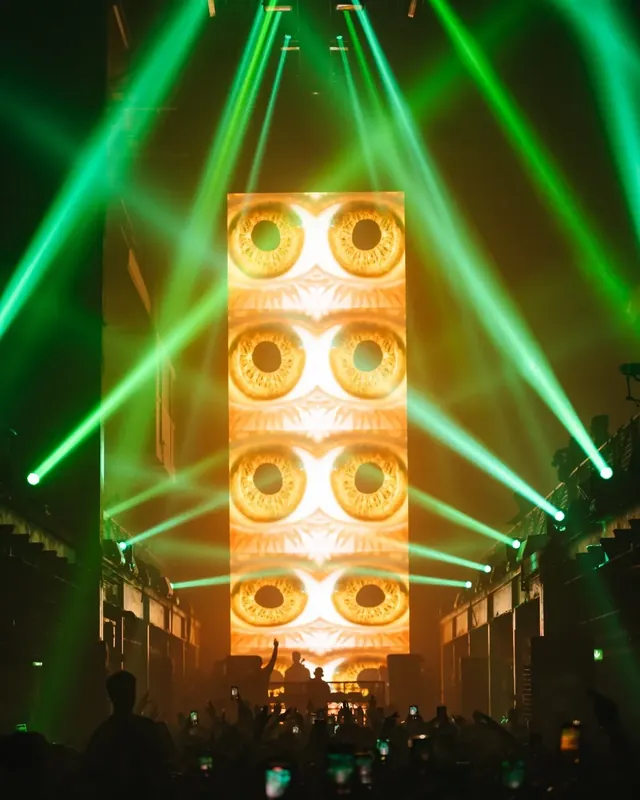DnB Allstars x Hedex: Printworks London: Green beams framing the giant eyes screen tower above Printworks crowd
